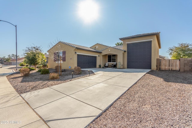 view of front of house with fence, concrete driveway, stucco siding, an attached garage, and a gate