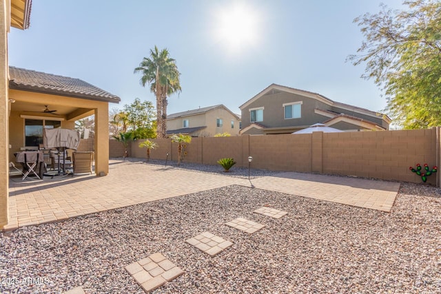 view of yard with a fenced backyard, a ceiling fan, and a patio area