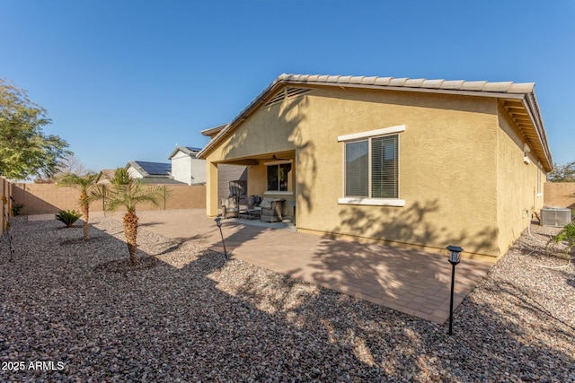 back of house featuring stucco siding, a patio, a fenced backyard, central AC unit, and a tiled roof