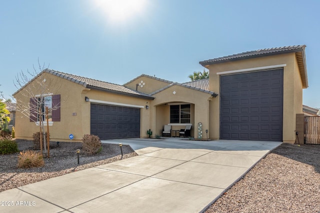 mediterranean / spanish home with stucco siding, a tile roof, fence, concrete driveway, and an attached garage