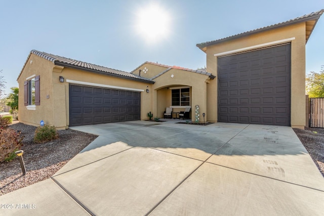 mediterranean / spanish-style home featuring fence, a tile roof, concrete driveway, stucco siding, and a garage