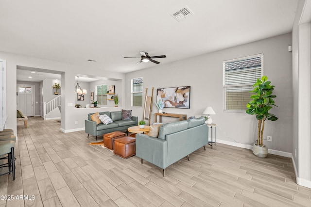 living room featuring light wood-type flooring, baseboards, a chandelier, and stairs