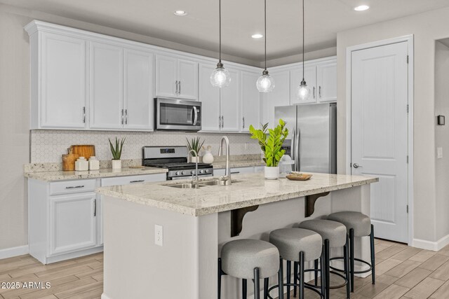 kitchen featuring stainless steel appliances, a sink, light wood-type flooring, baseboards, and recessed lighting