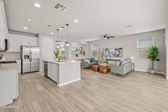 kitchen with appliances with stainless steel finishes, a sink, open floor plan, a ceiling fan, and recessed lighting