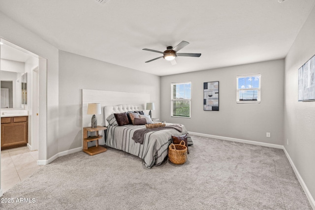 bedroom with light colored carpet, baseboards, ensuite bath, and a ceiling fan