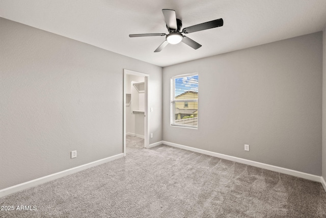 unfurnished bedroom featuring carpet floors, a walk in closet, baseboards, a ceiling fan, and a closet