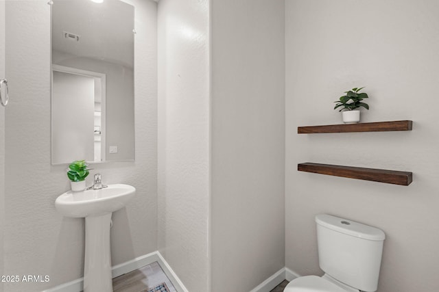 half bath featuring toilet and baseboards