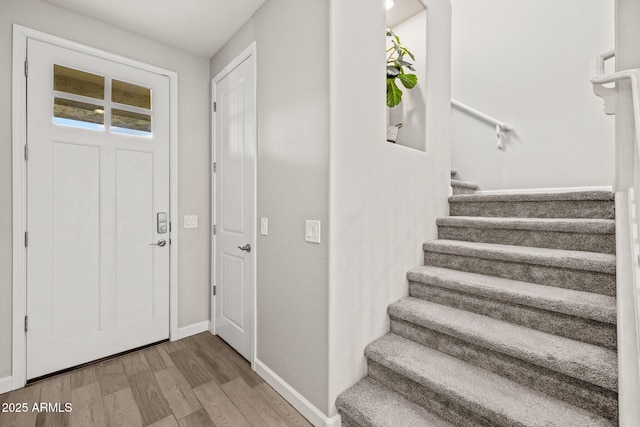 foyer with stairs, wood finished floors, and baseboards