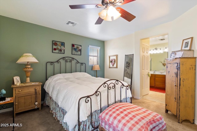 bedroom featuring visible vents, a ceiling fan, ensuite bathroom, and light colored carpet