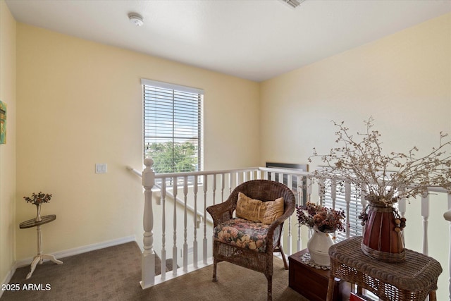 sitting room featuring carpet flooring, baseboards, and an upstairs landing