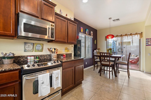 kitchen with visible vents, light tile patterned flooring, baseboards, dark stone counters, and stainless steel appliances