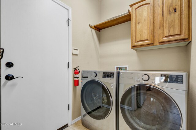 clothes washing area featuring washer and dryer, cabinets, and light tile patterned floors