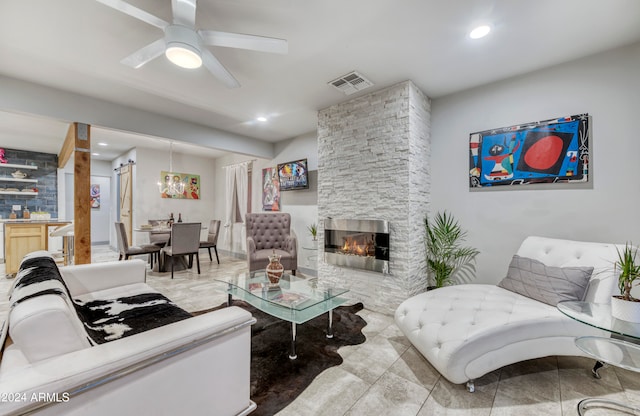 living room featuring ceiling fan and a stone fireplace