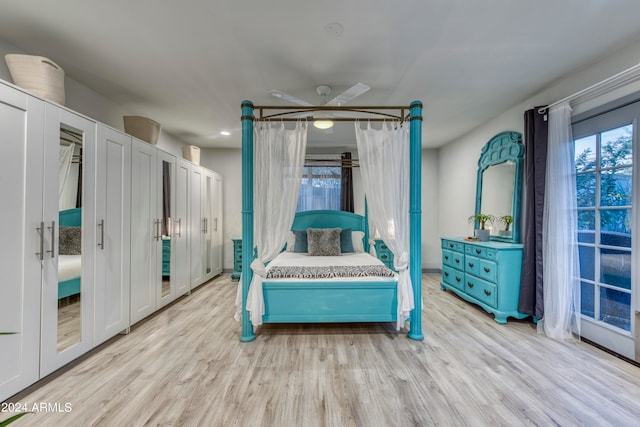 bedroom featuring ceiling fan, two closets, and light hardwood / wood-style floors