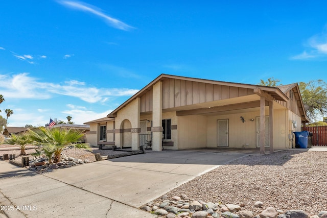 view of front facade with an attached carport, concrete driveway, and fence