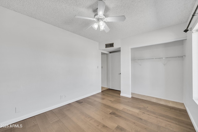 unfurnished bedroom with baseboards, a closet, wood-type flooring, and a textured ceiling