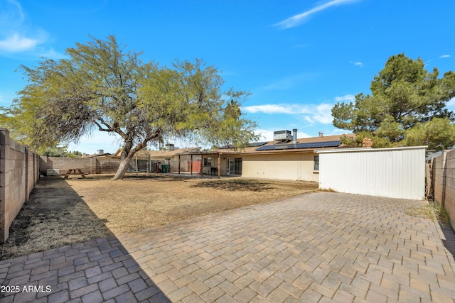 back of property featuring a patio area, solar panels, and a fenced backyard