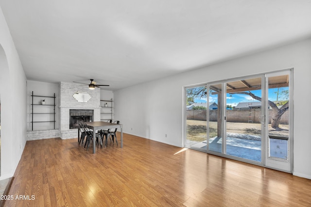 dining area with a ceiling fan, wood finished floors, and a fireplace