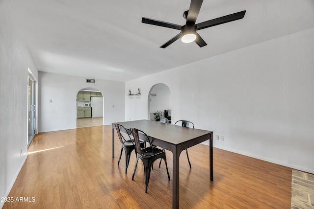 dining room with visible vents, arched walkways, light wood-style floors, and ceiling fan