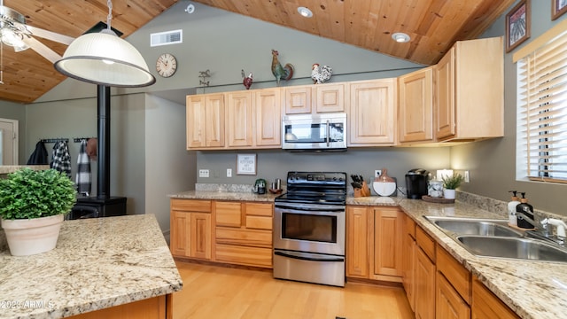 kitchen with lofted ceiling, stainless steel appliances, sink, decorative light fixtures, and light brown cabinetry