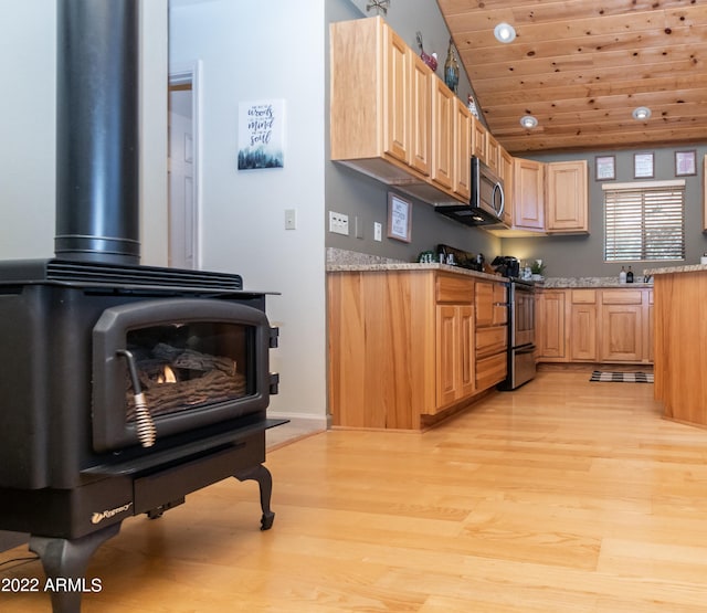 kitchen with appliances with stainless steel finishes, light wood-type flooring, wood ceiling, a wood stove, and light stone counters