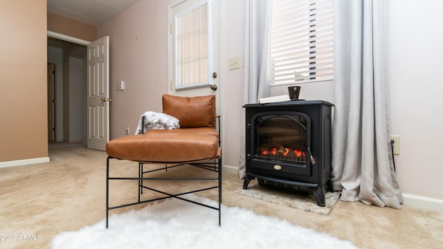 sitting room with a wood stove and light colored carpet