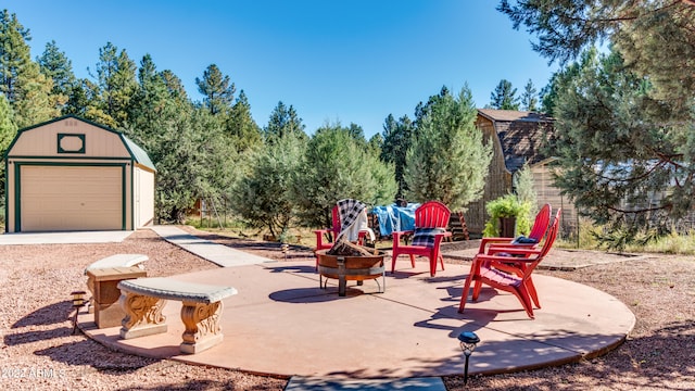 view of patio featuring a fire pit, an outbuilding, and a garage