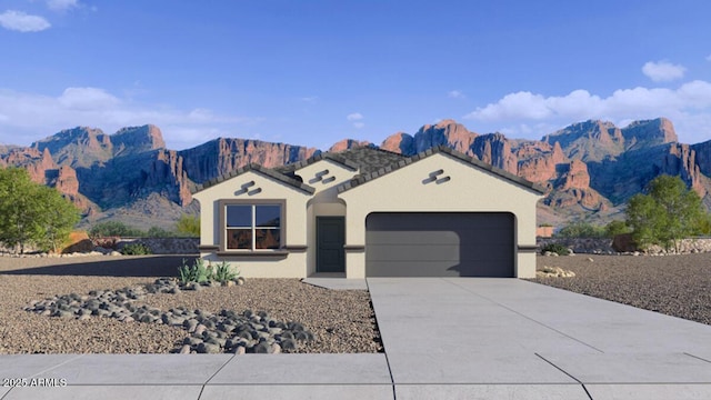 view of front facade featuring a garage, a mountain view, driveway, and stucco siding