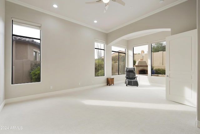 unfurnished room featuring a fireplace, ceiling fan, crown molding, and carpet floors