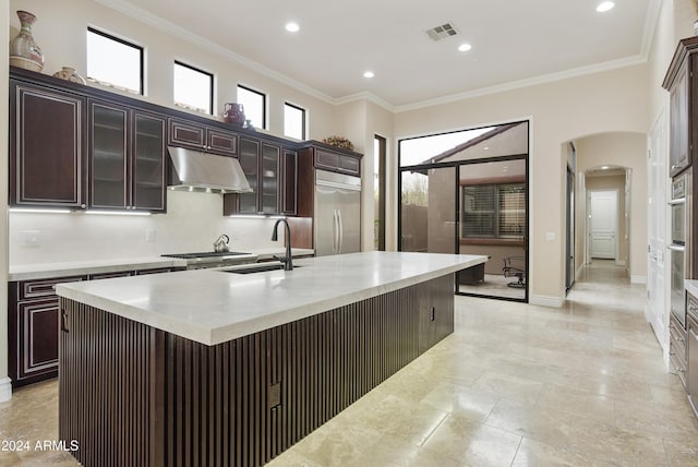 kitchen featuring dark brown cabinetry, sink, crown molding, a kitchen island with sink, and appliances with stainless steel finishes