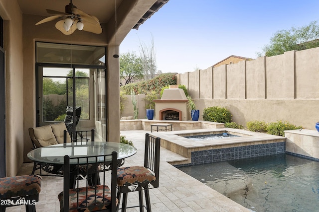 view of patio / terrace with ceiling fan, an in ground hot tub, and a tile fireplace