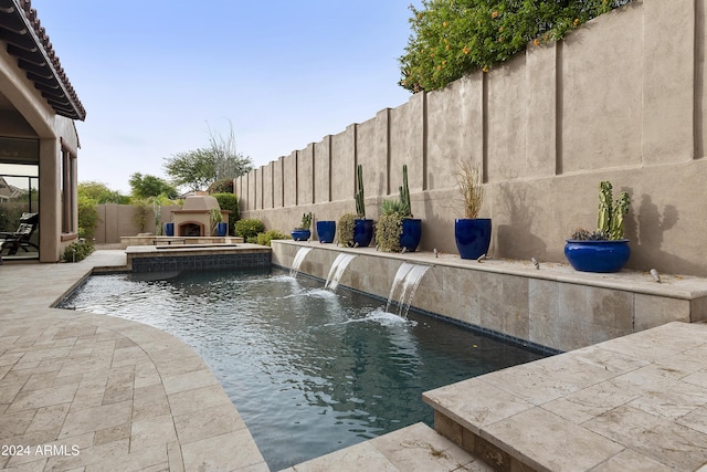 view of swimming pool with a patio area, pool water feature, and exterior fireplace