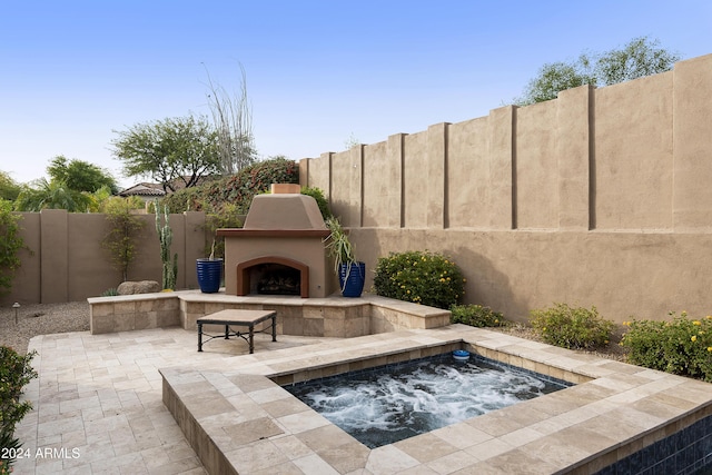 view of patio / terrace with an in ground hot tub and an outdoor fireplace