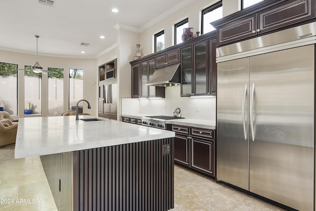 kitchen with sink, hanging light fixtures, stainless steel appliances, crown molding, and a center island with sink