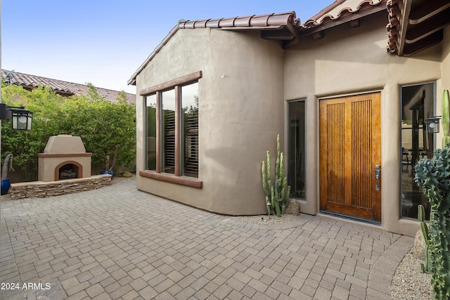 entrance to property featuring a patio area and exterior fireplace