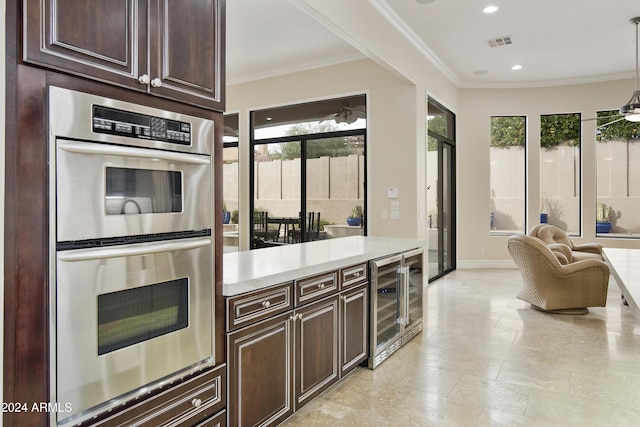 kitchen with pendant lighting, wine cooler, ornamental molding, double oven, and dark brown cabinetry