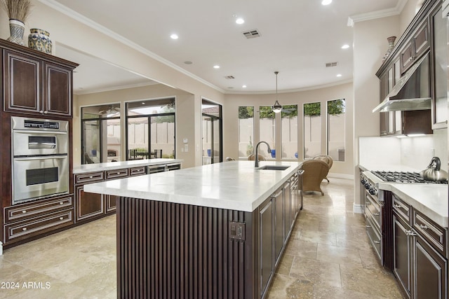 kitchen featuring stainless steel appliances, a kitchen island with sink, crown molding, sink, and hanging light fixtures