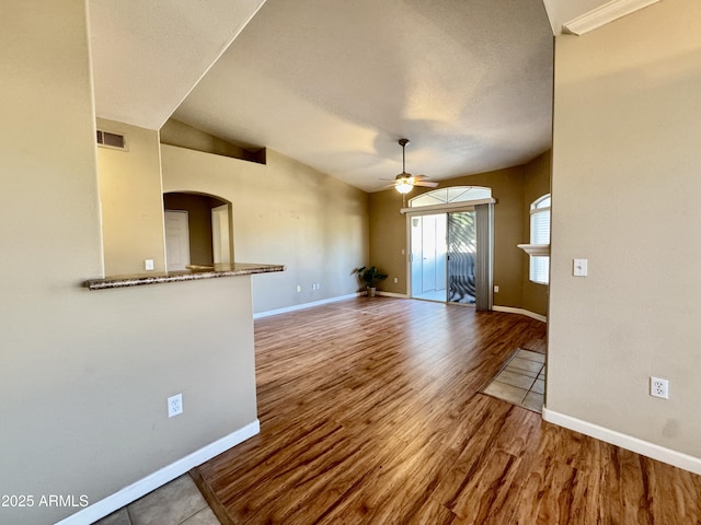 interior space with baseboards, arched walkways, ceiling fan, and wood finished floors