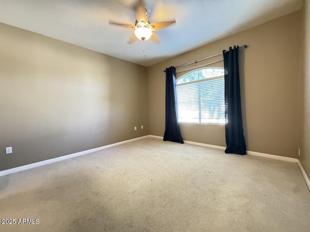 carpeted spare room with a ceiling fan and baseboards