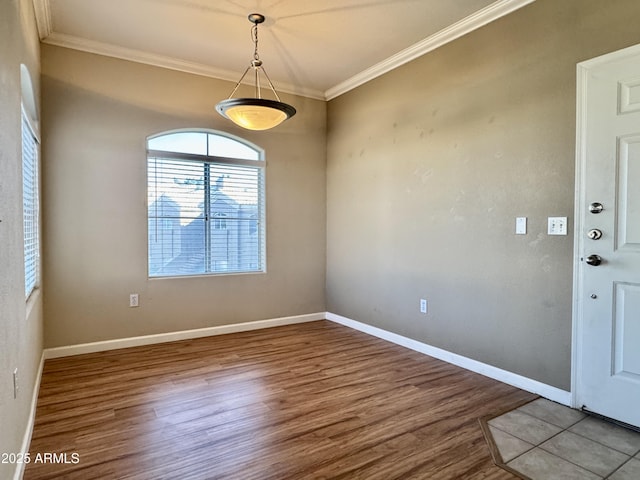unfurnished dining area featuring baseboards, ornamental molding, and wood finished floors