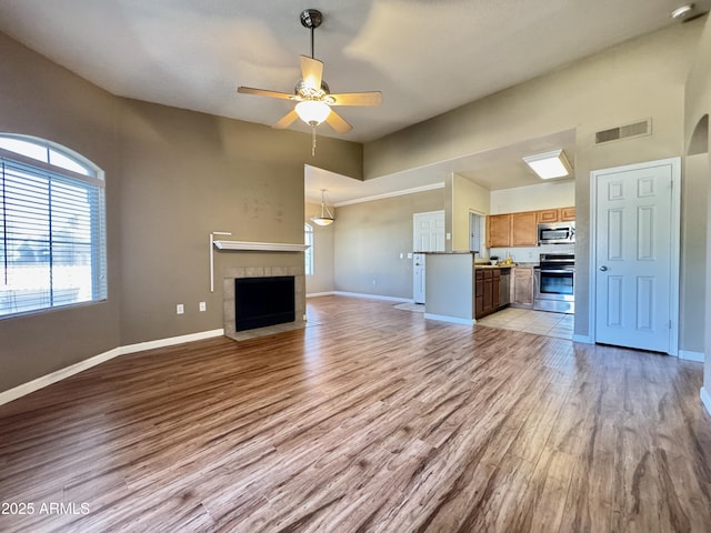unfurnished living room featuring baseboards, visible vents, ceiling fan, and light wood finished floors