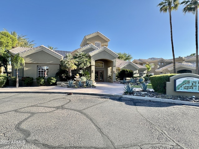 view of front of house featuring a residential view, stucco siding, french doors, and a tile roof