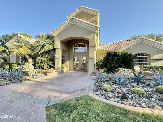 view of front of home with a tiled roof, french doors, and stucco siding