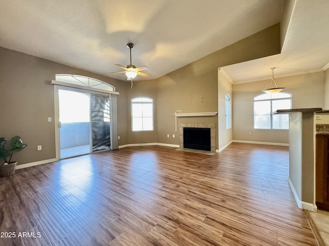 unfurnished living room with wood finished floors, a wealth of natural light, and a tile fireplace