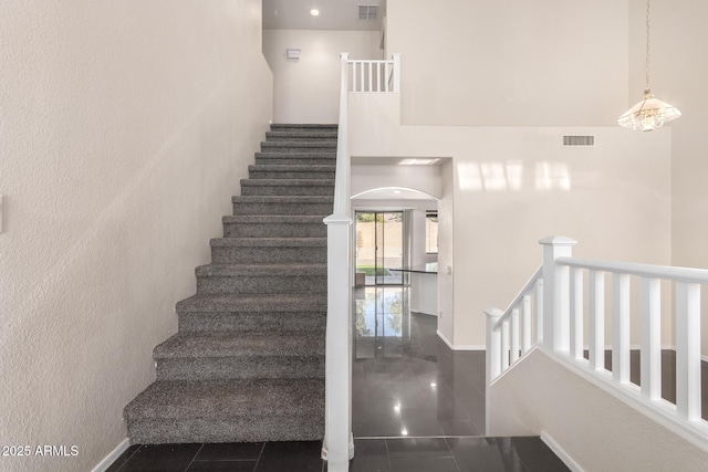 staircase with tile patterned flooring and a high ceiling