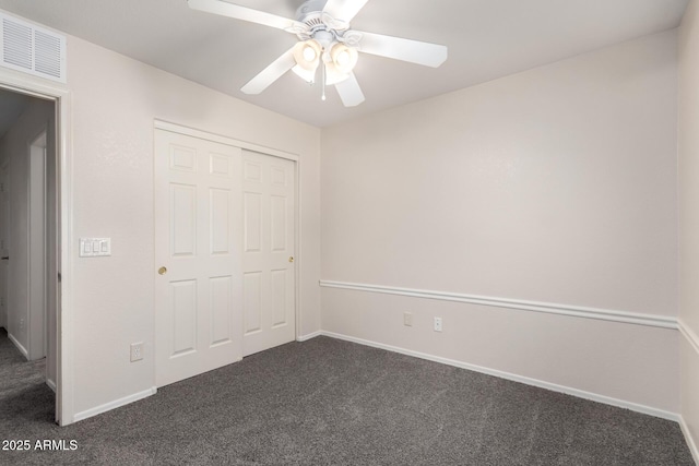 unfurnished bedroom with ceiling fan, a closet, and dark colored carpet