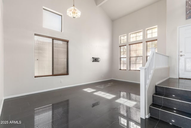 unfurnished living room featuring dark tile patterned floors, a chandelier, and a high ceiling