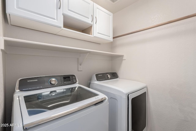 clothes washing area featuring cabinets and washing machine and clothes dryer