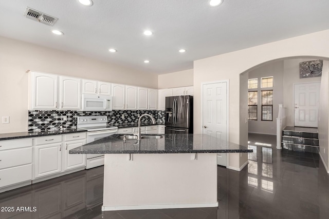 kitchen with white cabinetry, an island with sink, sink, dark stone counters, and white appliances