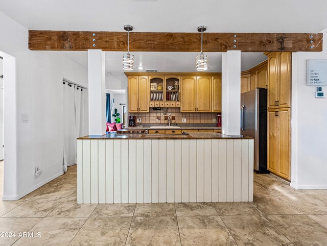 kitchen featuring light tile patterned flooring, sink, decorative light fixtures, backsplash, and stainless steel refrigerator